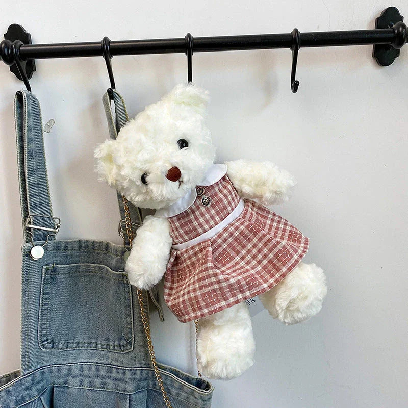 A plush teddy bear crossbody messenger bag with an adjustable shoulder strap and a zippered interior pocket for convenient storage.