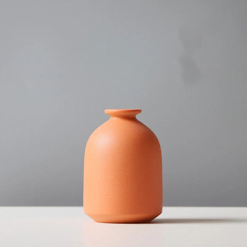 Stylish ceramic vases in various colors, including brown, black, green, and orange, for modern home decor