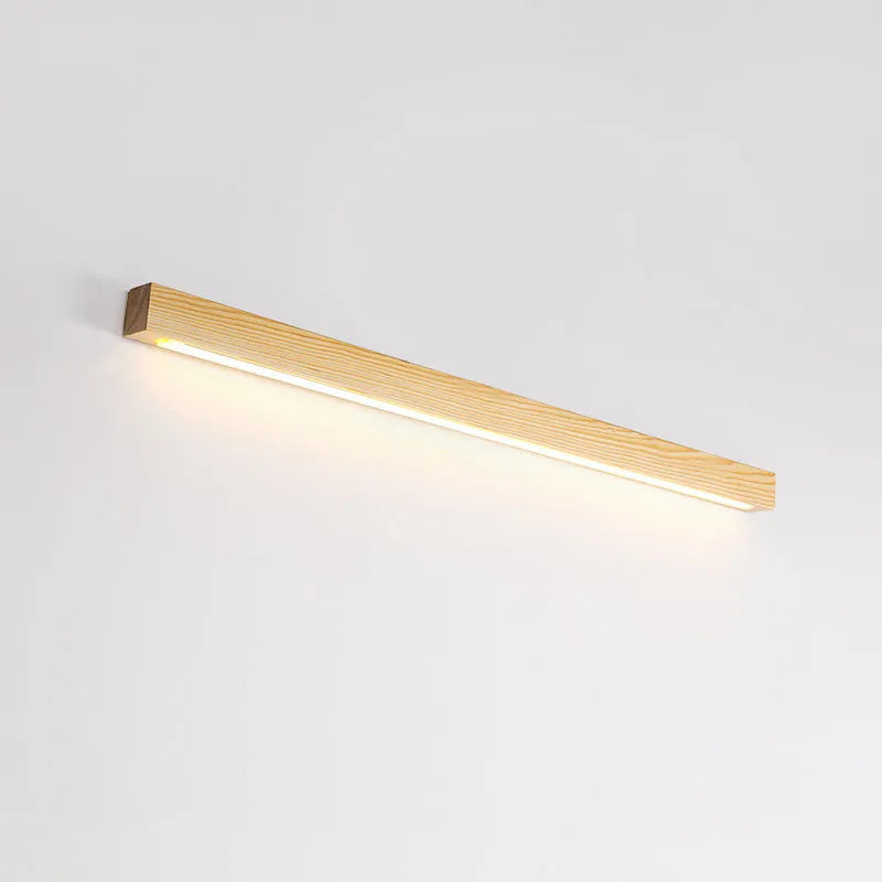 A long, slim walnut-coloured wooden strip wall lamp with an integrated LED light source mounted on a plain wall.