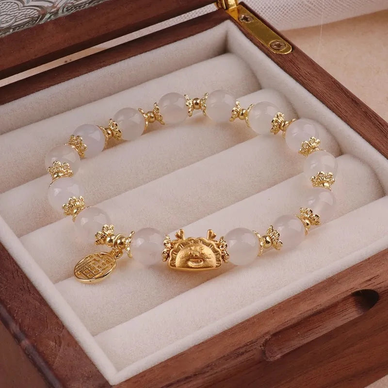 A women's glass glazed bracelet with floral and zodiac animal charms in red, pink, and white pearl beads.