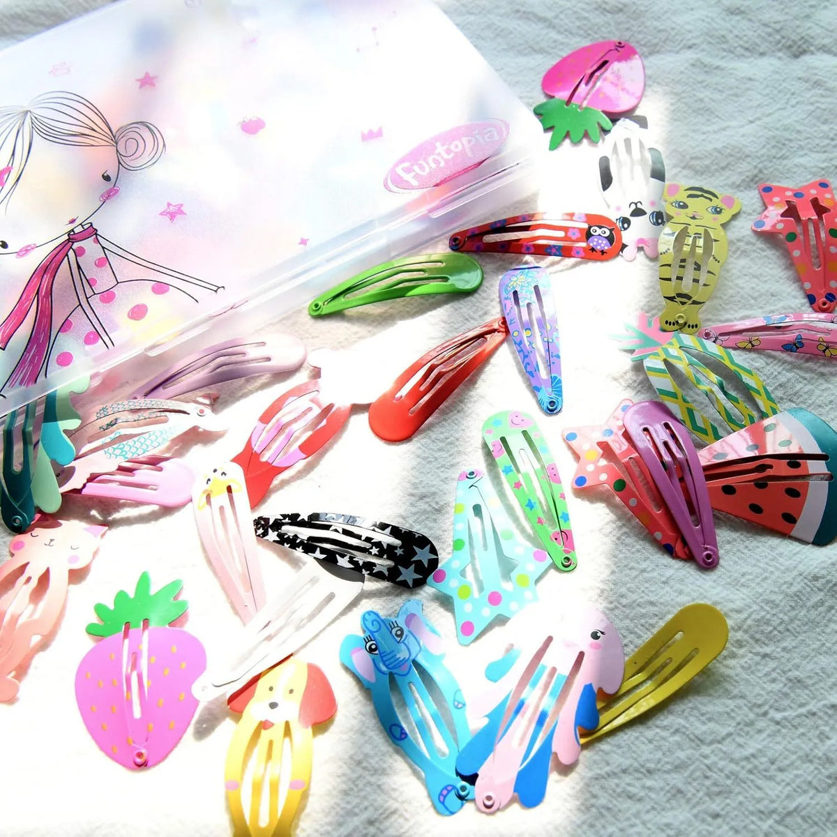 Assortment of 100 brightly coloured metal hair clips with cartoon designs of animals, fruits, crowns, stars, and drop shapes.