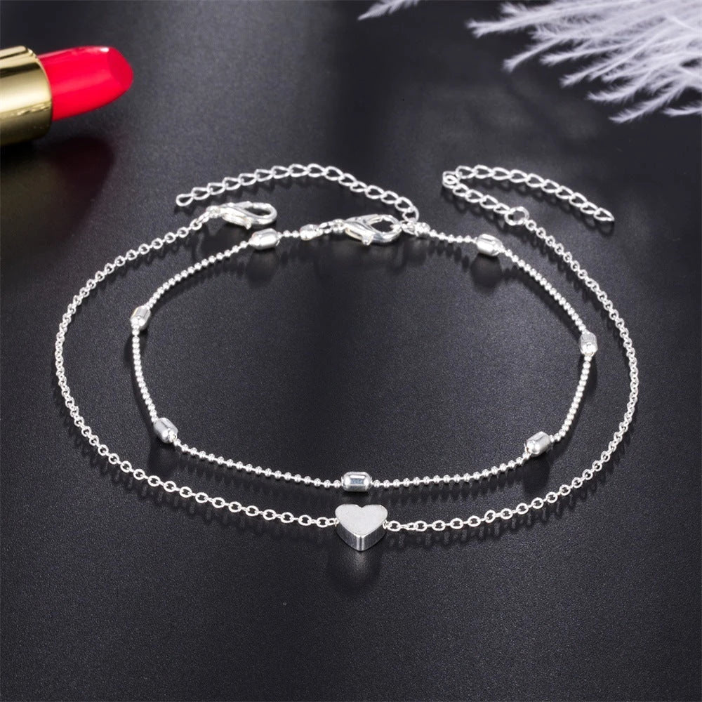 Trendy heart-shaped anklet with double-layered design and retro beach ball chain in gold, silver, and silvery colors.