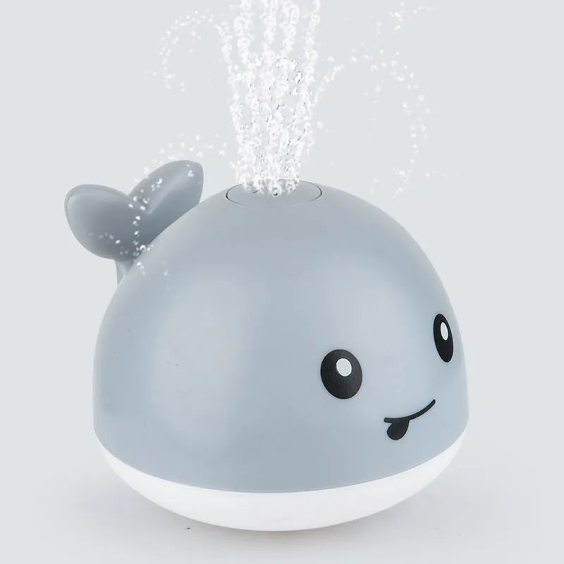 Automatic water-spraying whale bath toy with colourful lights floating in bath water.