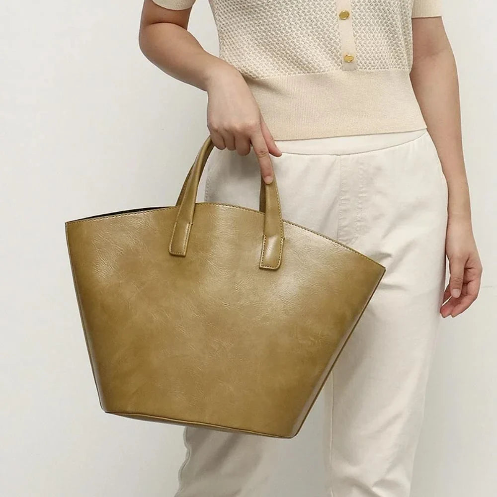Elegant vegan leather tote bag with a unique bucket shape, versatile carrying options, and a secure zip liner for all your daily essentials.