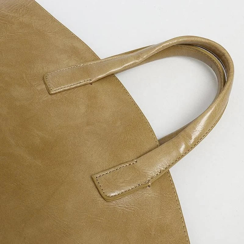 Elegant vegan leather tote bag with a unique bucket shape, versatile carrying options, and a secure zip liner for all your daily essentials.