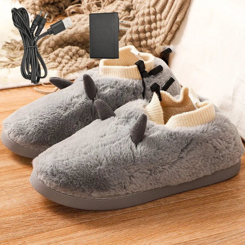 A pair of grey USB heated slippers with a connected cable, showing the soft velvet upper and plastic sole.