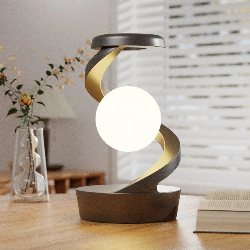 A rotating moon-shaped desk lamp with a wireless charging pad for smartphones, featuring a sleek and modern design.