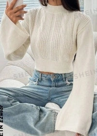 A woman wearing a cozy, flared sleeve sweater in a classic black color