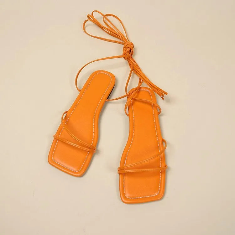 Women's black flat sandals with bandage ankle wrap and front lace-up fastening on a white background.