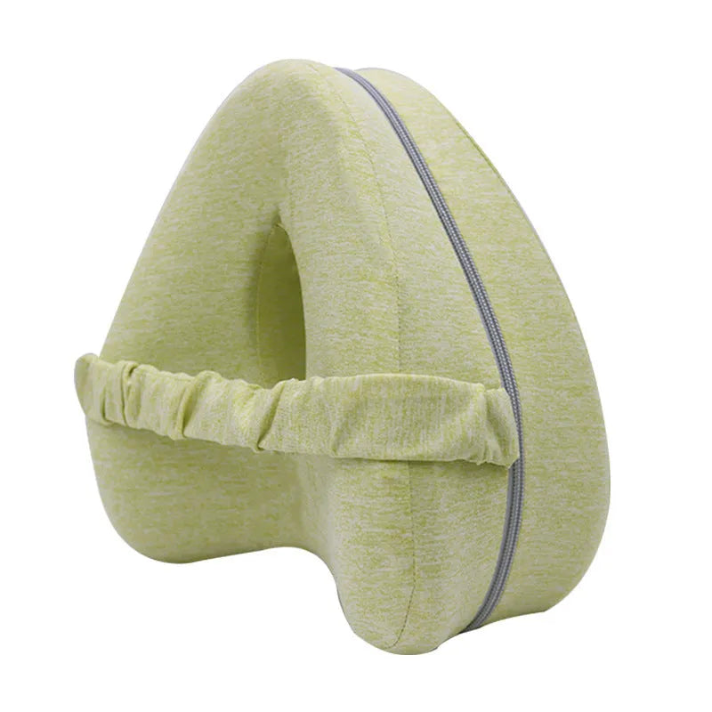 Dark blue jacquard heart-shaped memory foam leg pillow for adults on a bed.
