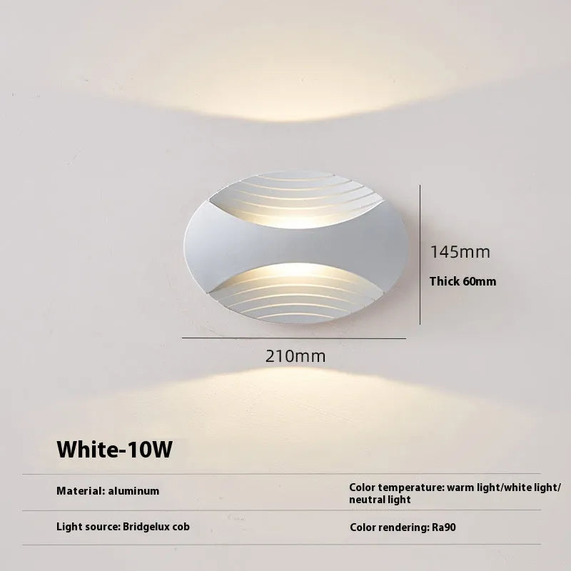 Modern aluminium wall lamp in black finish mounted beside a bed, emitting warm LED light.