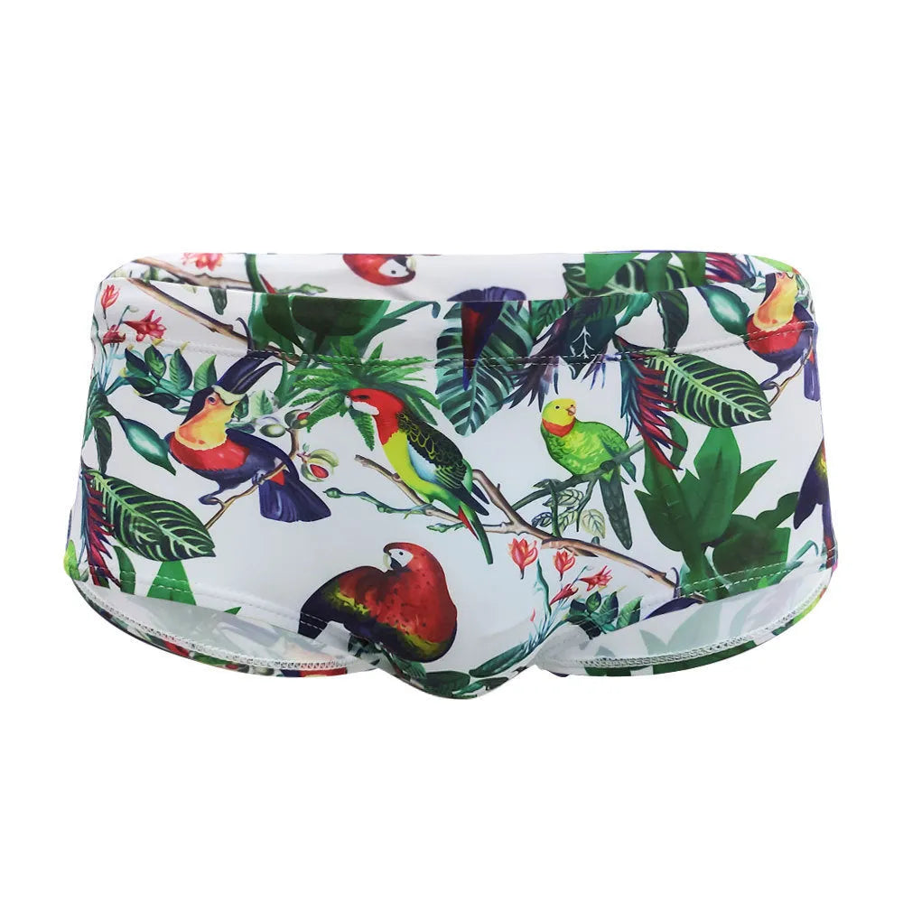 Men's blue swimming trunks with a detailed floral and bird print pattern, shown in a brief style.