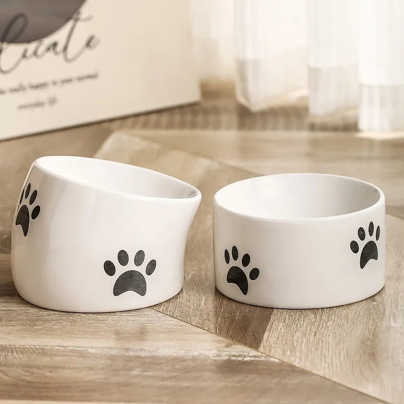 Ceramic cat bowl with high foot and cat's paw base in an oblique mouth design.