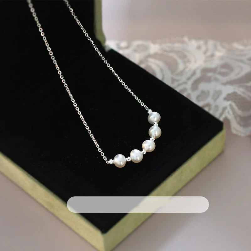 A close-up shot of a natural freshwater pearl necklace with a silver chain in a stylish multi-chain design.