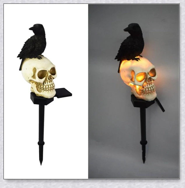 A solar-powered landscape light in the shape of a crow perched on a skull, providing an eerie and captivating outdoor decoration.