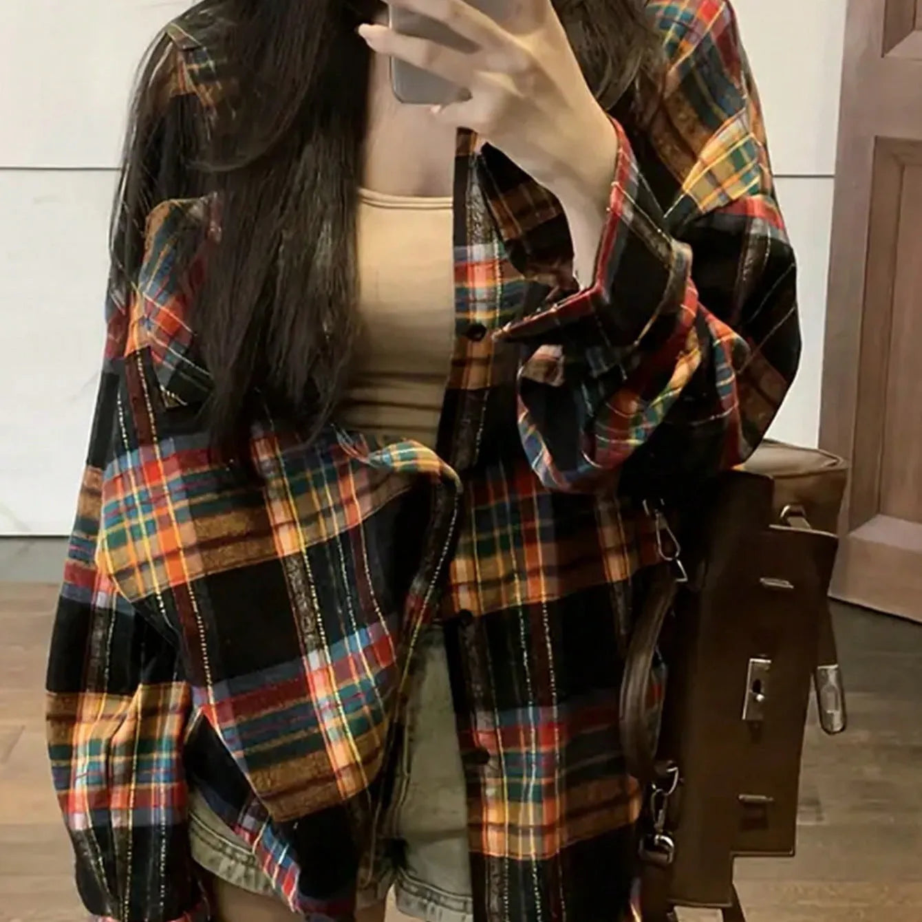 A woman modelling a loose-fit black, green, and purple plaid shirt with long sleeves.