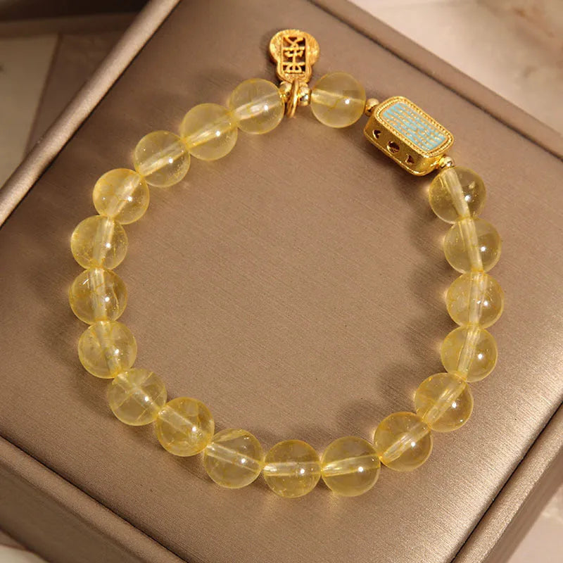 Women's bracelet made from yellow citrine crystal with rhinestone decoration on a white background.