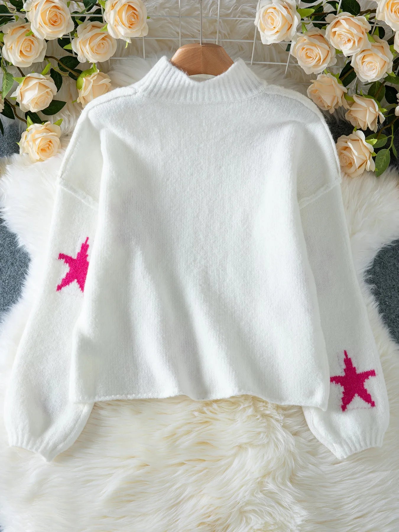 White women's turtleneck pullover with a black star pattern, loose fit, and long sleeves.