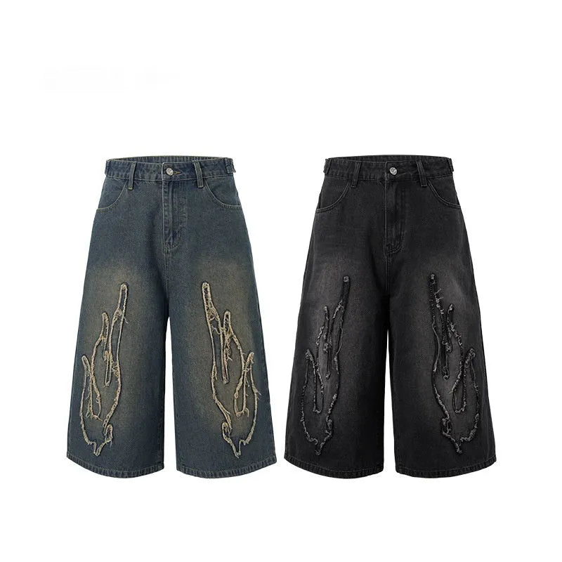 Men's black denim shorts with a cropped flame embroidery patch on the leg.