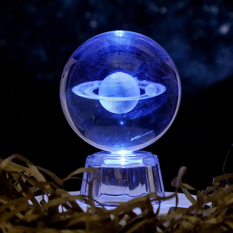 Transparent crystal ball ornament with inner carving of clouds, shown on a wooden table.