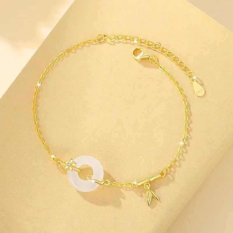 Gold-colour women's bracelet with peace symbol buckle and white chalcedony stone on silver band.