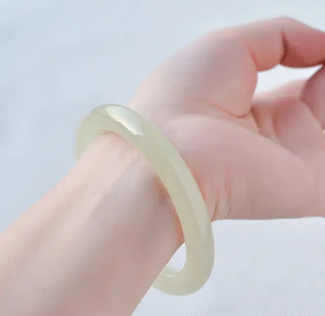 Ice-like silk jade bracelet with winding silk design and round bar beads on a wrist.