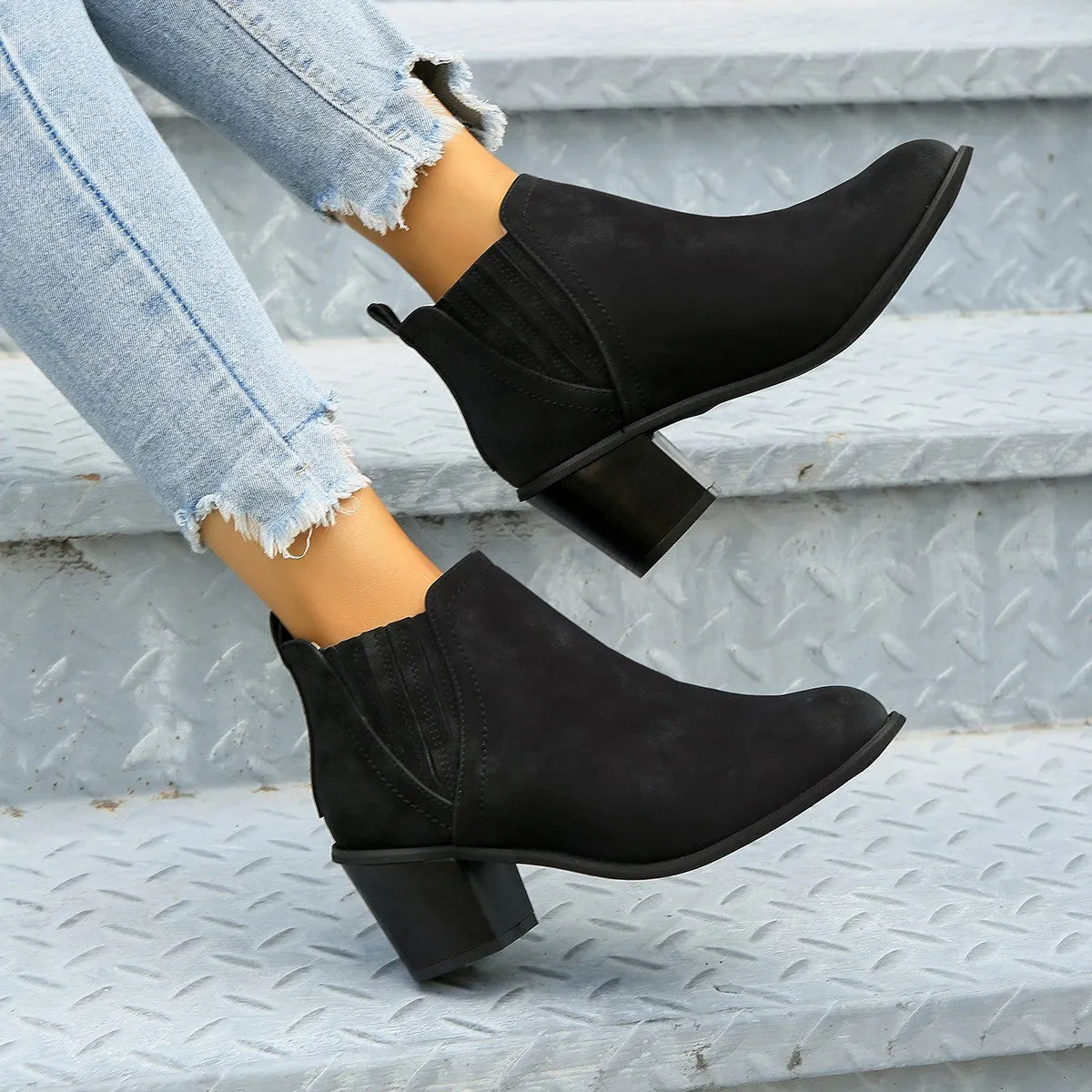 Black and brown women's ankle boots with a pointed toe and thick square low heel, slip-on design.