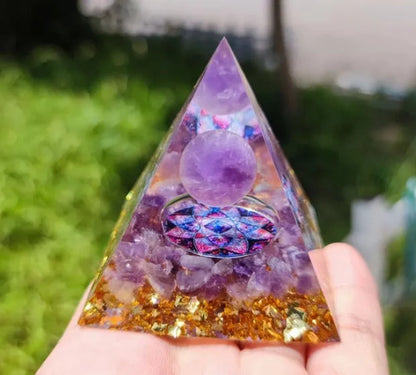 A small 6cm clear epoxy resin pyramid ornament containing pieces of natural crystal gravel on a flat surface.