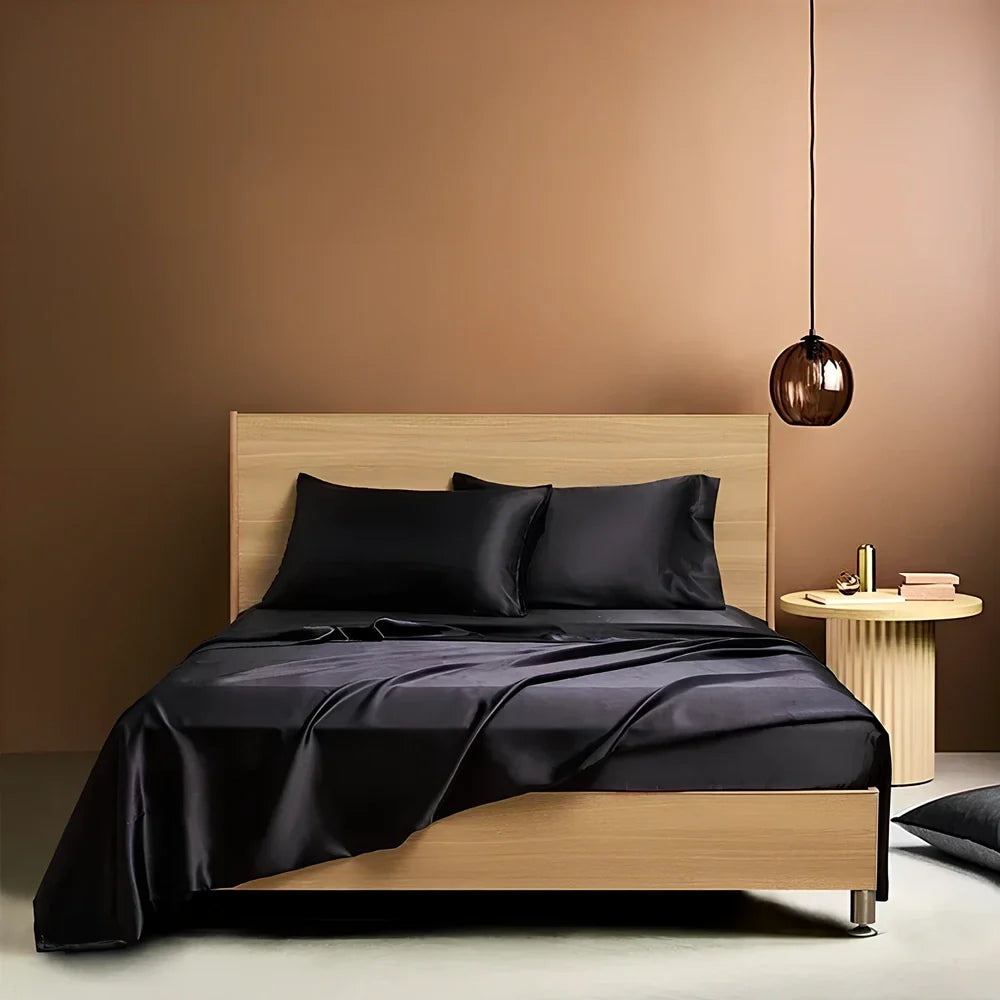 Navy blue floral pattern silk bedding set with quilt cover, fitted sheet, and two pillowcases on bed