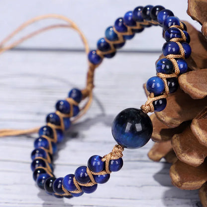 Handmade geometric pull bracelet woven from blue tigereye stone beads on a wrist.