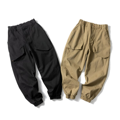 Black cotton casual pants with large pockets, tapered legs, and ankle ties on a hanger.
