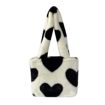 Soft, plush heart-shaped handbag in various vibrant colors with a magnetic closure and interior phone compartment