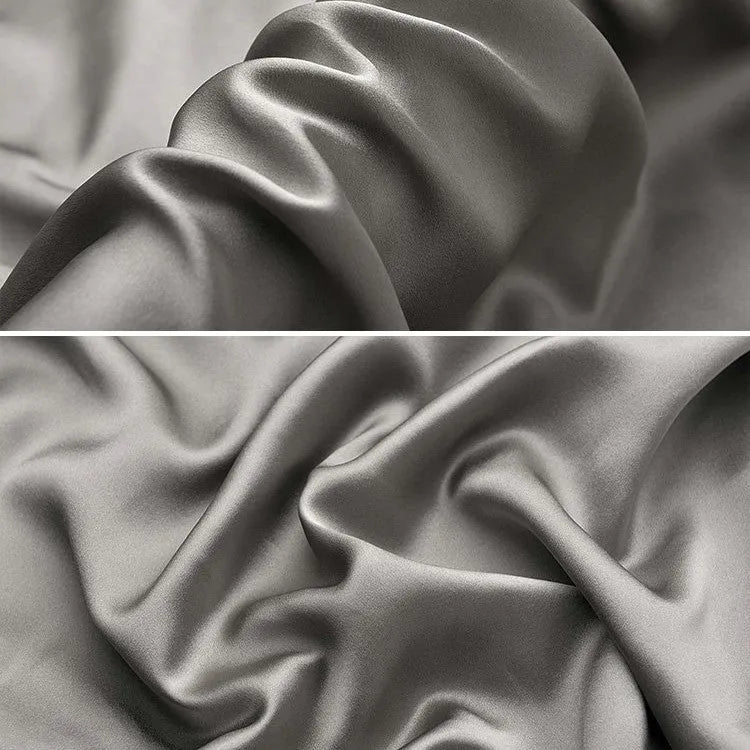 Dark grey silk pillowcase with envelope closure on a bed.