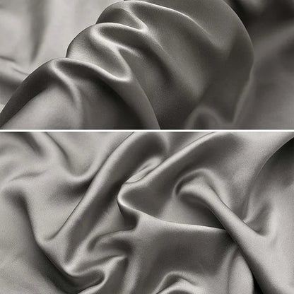 Dark grey silk pillowcase with envelope closure on a bed.