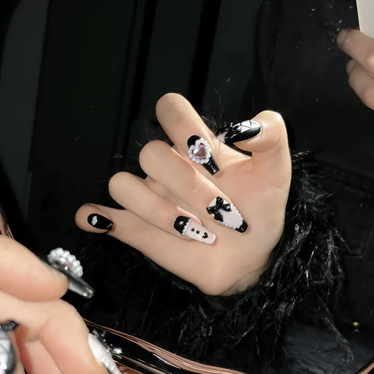 Hand-painted black and pink heart design on reusable plastic false nails with bow and cat's eye details.