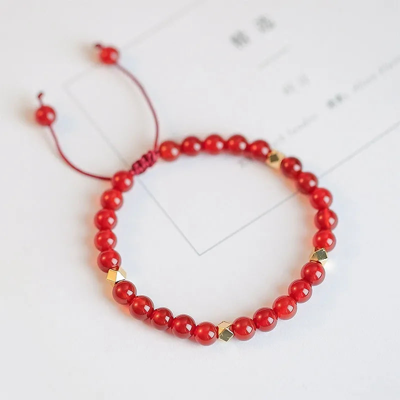 Hand-woven red agate beads bracelet with lucky charm in ethnic style, showing diamond-shaped beads.