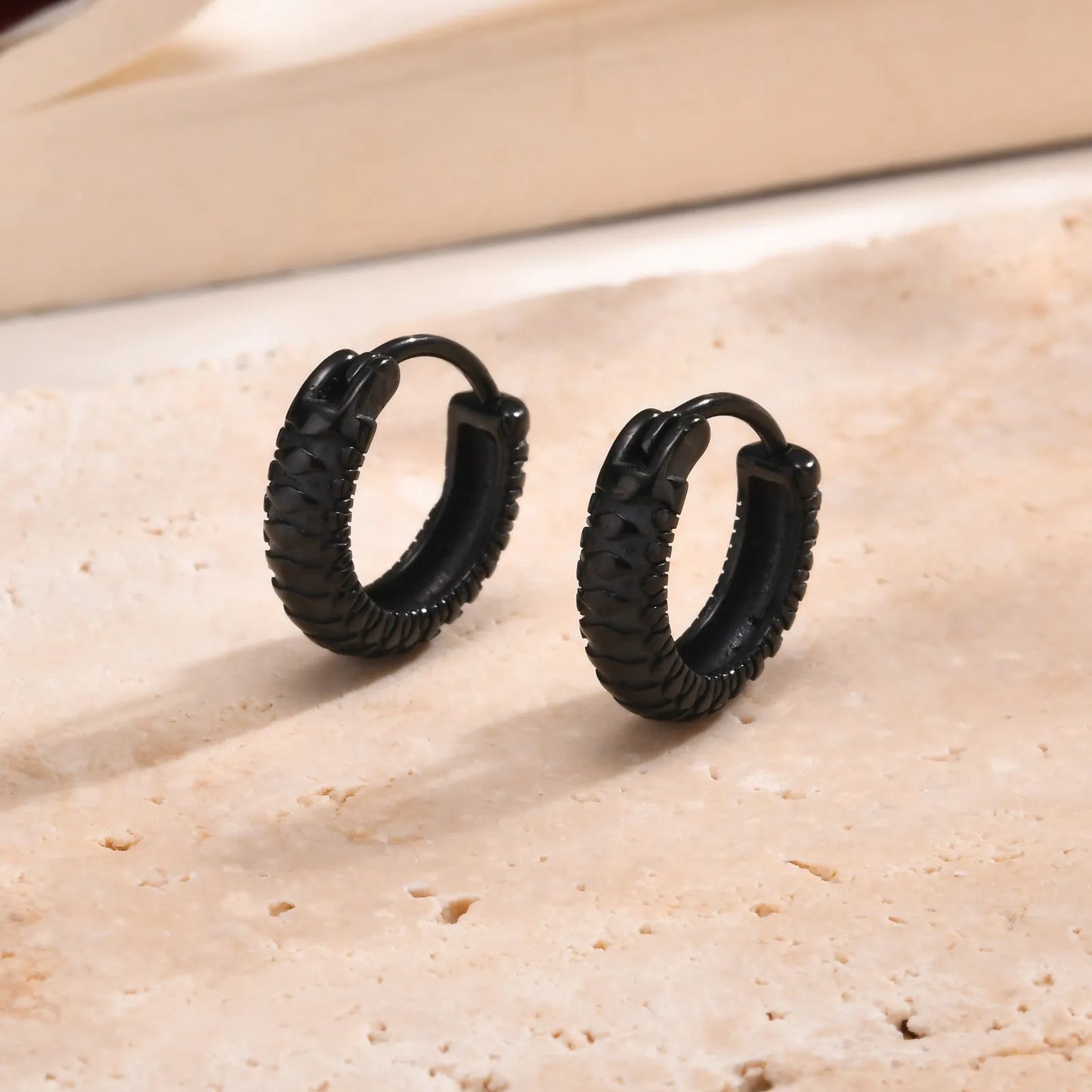 Pair of stainless steel earrings with snake pattern texture in black finish, 1.5cm diameter