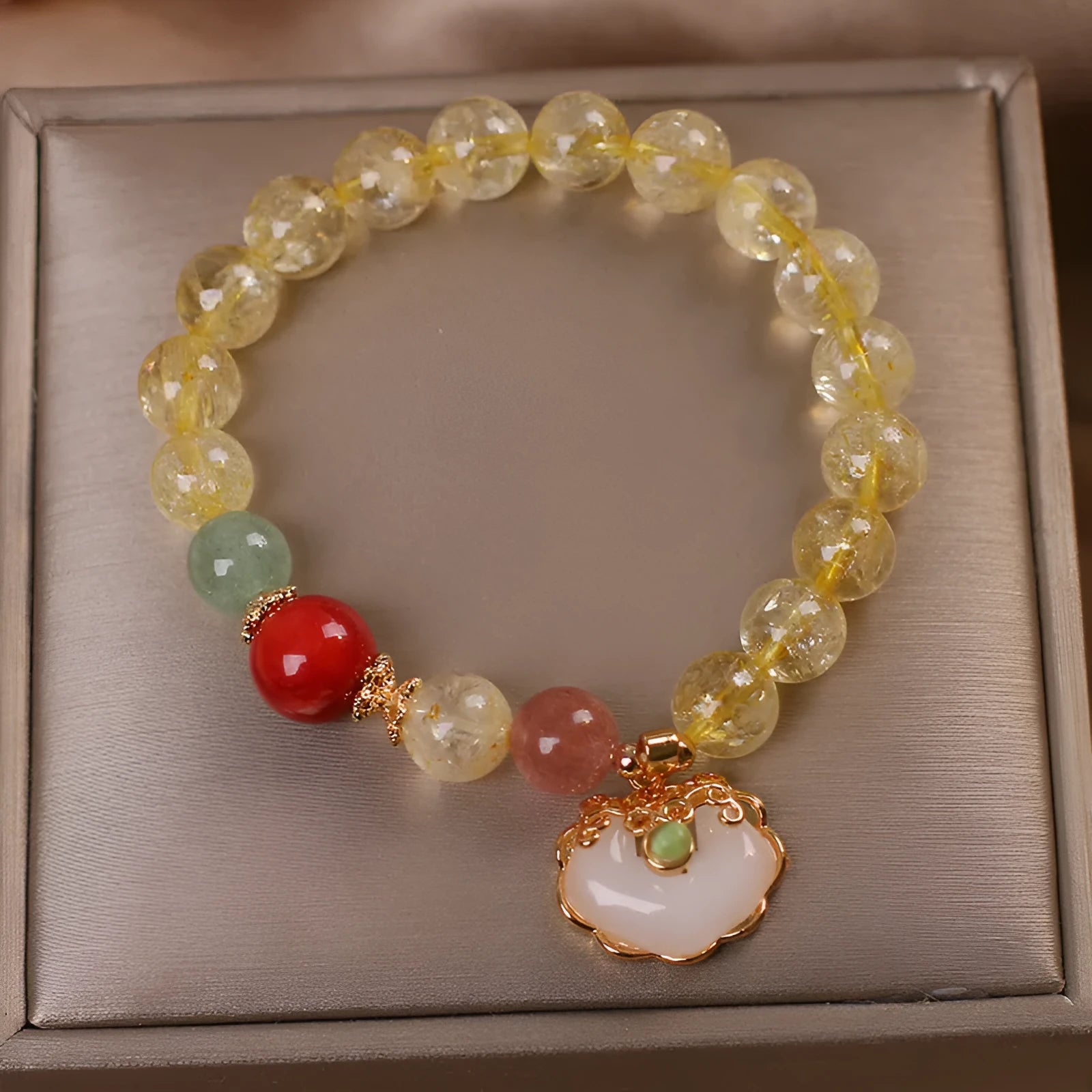 Women's yellow citrine jade ruyi pendant bracelet on wrist, alloy construction.