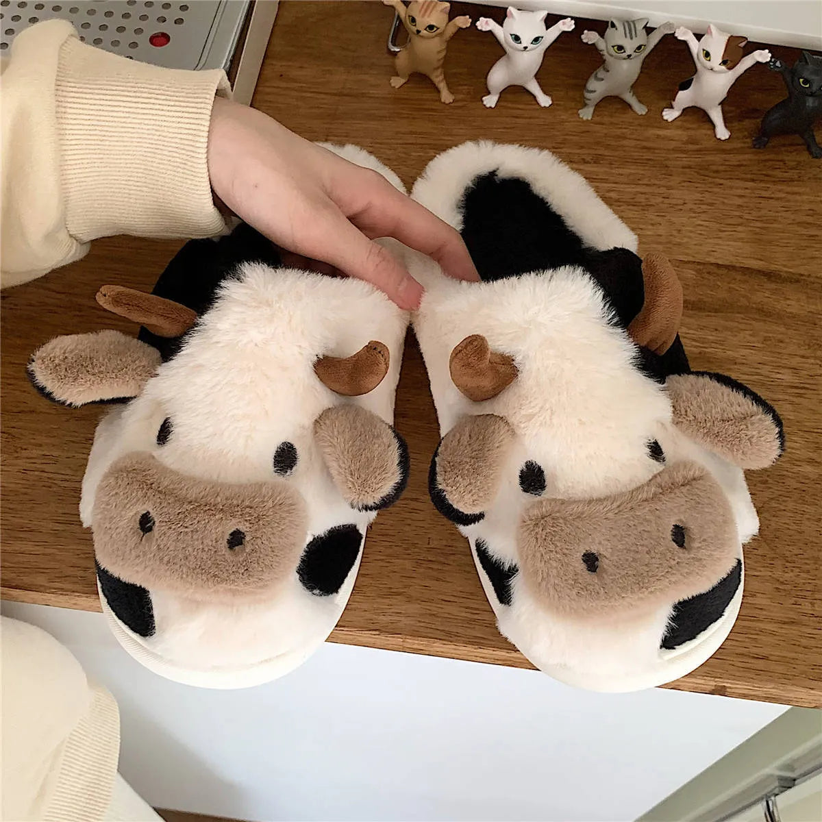 White cow-themed plush slippers with a non-slip textured sole for women.