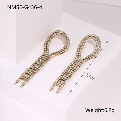 Gold-coloured women's earrings with a love heart shape, star details and dangling diamond-style tassels on a white background.