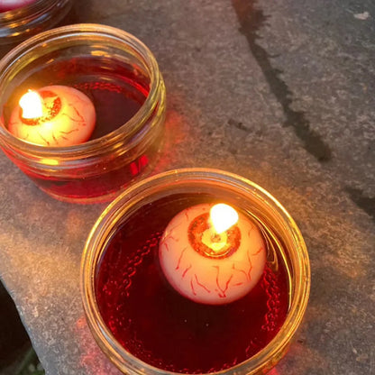 Red oval paraffin floating candle resembling eyeball in Halloween water display