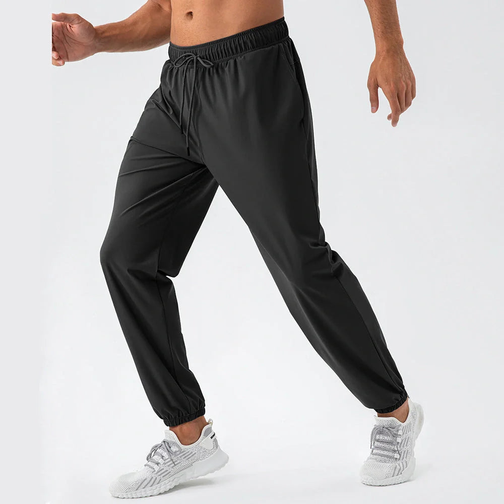 Men's lightweight nylon track pants in various colors, featuring a relaxed, flexible fit for active lifestyles