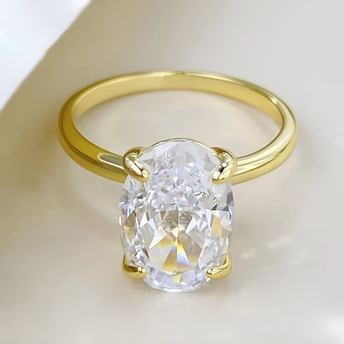 Oval silver ring with four-prong setting and a hand-cut stone on a finger.