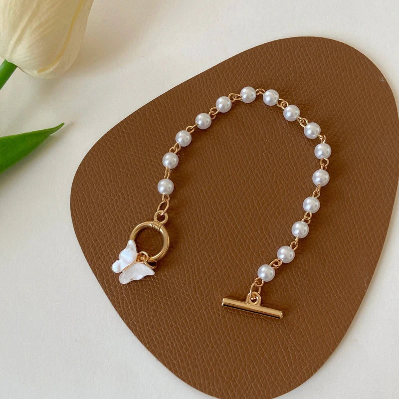 Gold charm bracelet with pearl and butterfly design for women