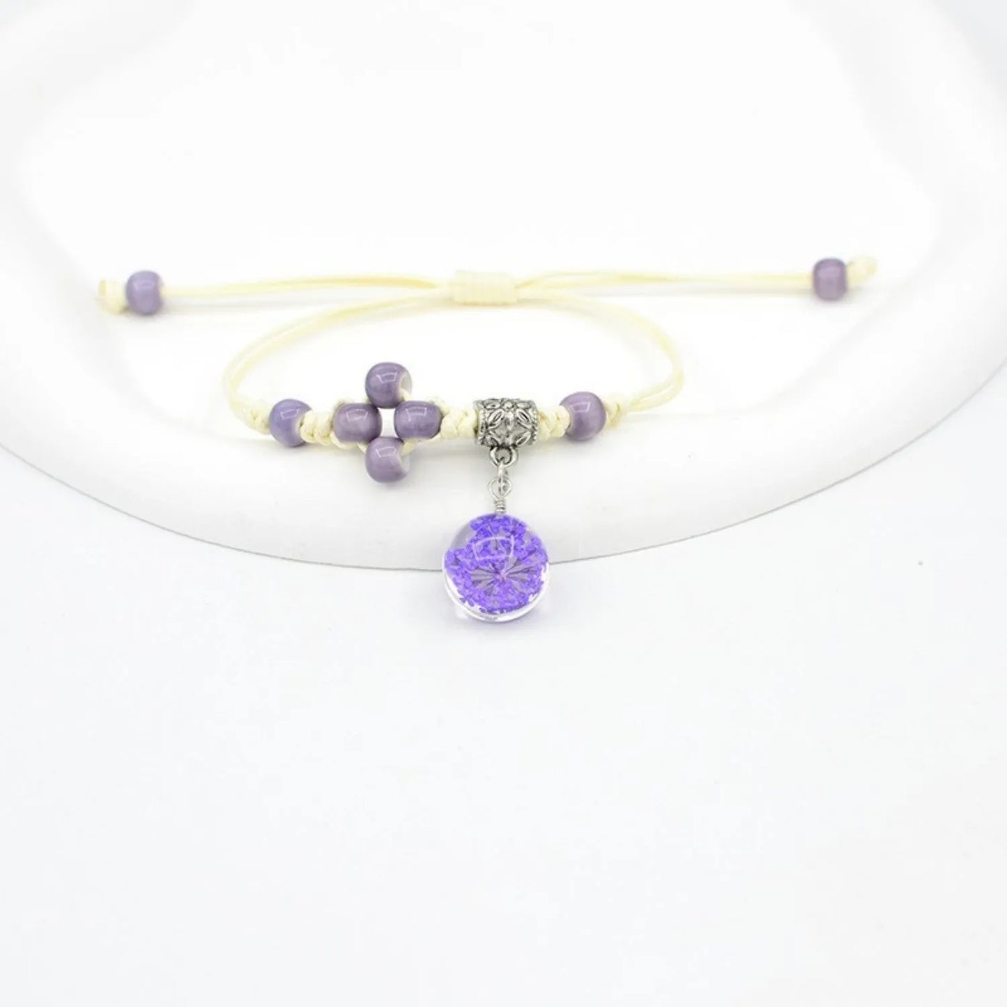 Hand-woven glass bracelet with large 1.4 cm beads containing real dried flowers, shown in blue.