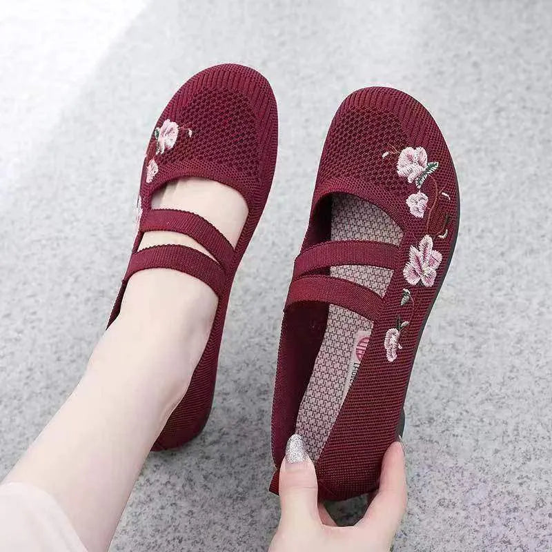 A pair of slip-on flat shoes with an elastic upper and rubber sole, shown in an embroidered colour option.