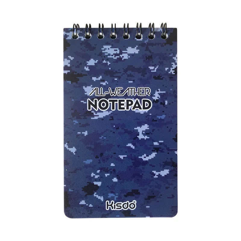 Spiral-bound waterproof notepad in camouflage colour, open on a desk with a pen, showing stone paper pages.