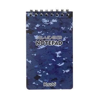 Spiral-bound waterproof notepad in camouflage colour, open on a desk with a pen, showing stone paper pages.