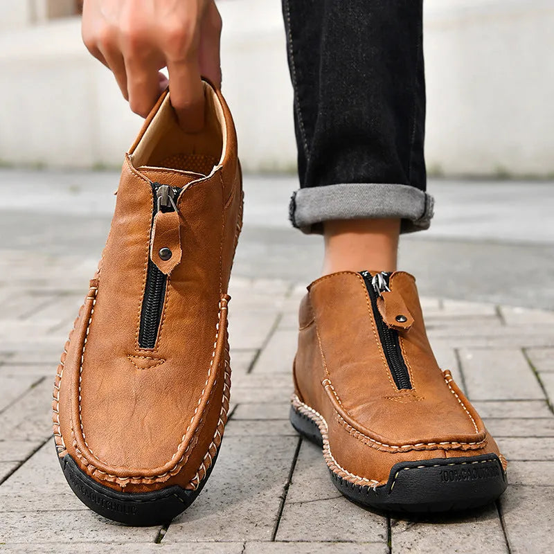 Men's slip-on loafers in black with round toe and sewing thread details, showing rubber sole