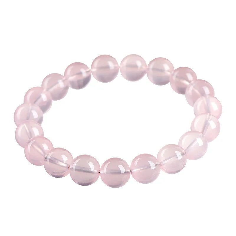 A polished natural starlight crystal round bead bracelet in pink, showing different size options on a wrist.